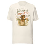 Cream unisex t-shirt reading In My Farmers Market Era with a watercolor illustration of a dachshund puppy in a market tote basket with flowers and bread