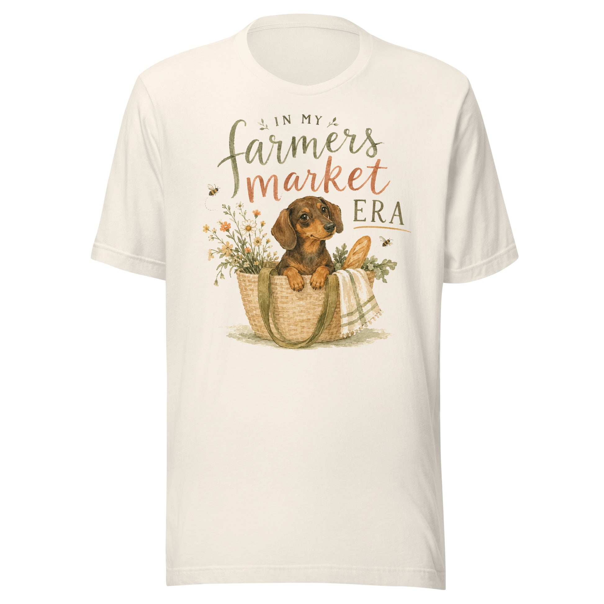 Cream unisex t-shirt reading In My Farmers Market Era with a watercolor illustration of a dachshund puppy in a market tote basket with flowers and bread
