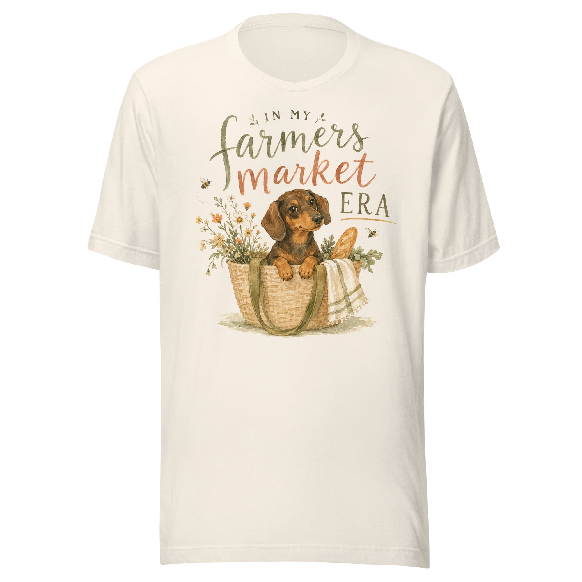 Cream unisex t-shirt reading In My Farmers Market Era with a watercolor illustration of a dachshund puppy in a market tote basket with flowers and bread